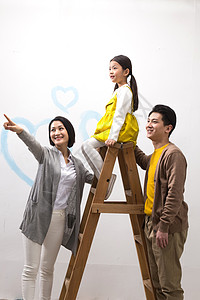 儿童手拿画刷关爱青年夫妇青年女人快乐家庭装修房子背景