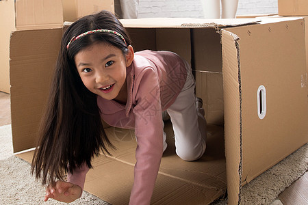 可爱的创造力兴奋小女孩藏在纸箱里图片