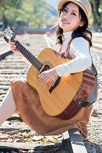 青年女人坐在铁路边弹吉他图片