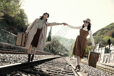 旅行者不看镜头休闲青年闺蜜手牵手走在铁轨上图片