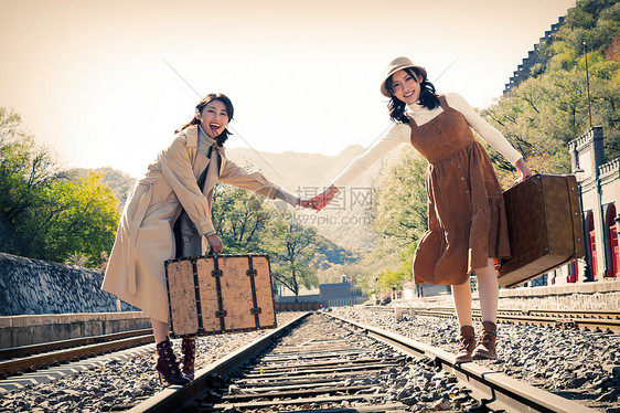 旅途户外放松青年闺蜜手牵手走在铁轨上图片