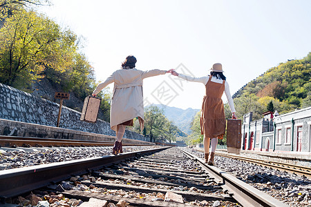 旅途放松美女青年闺蜜手牵手走在铁轨上图片