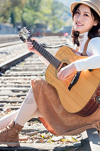 自由图片视觉效果音乐人青年女人坐在铁路边弹吉他图片