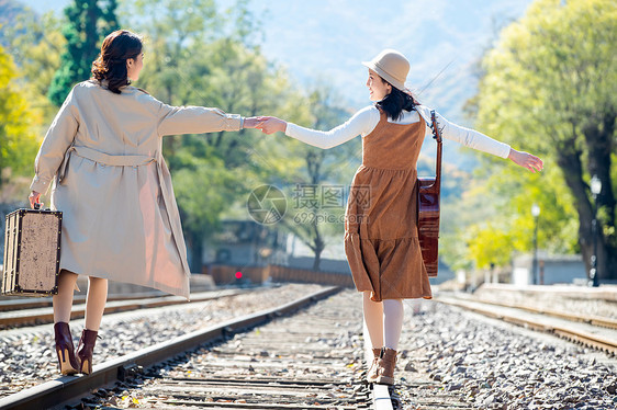 青年女人旅途旅行者青年闺蜜手牵手走在铁轨上图片