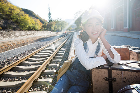 道路坐着日光青年女人坐在火车站站台上图片