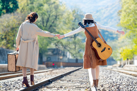 非都市风光户外郊区青年闺蜜手牵手走在铁轨上图片