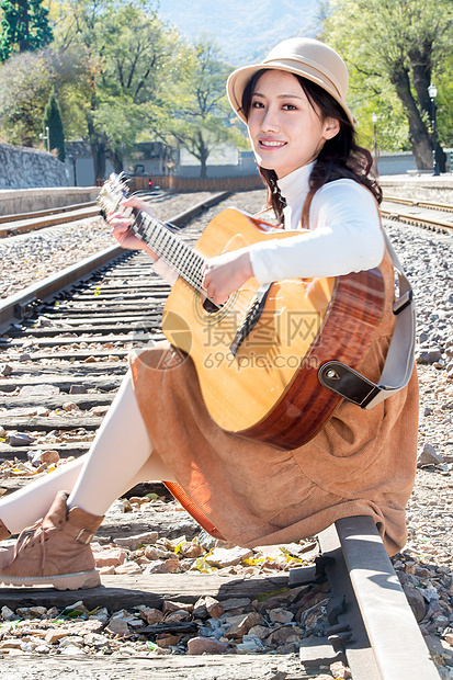复古女人坐在铁路边弹吉他图片