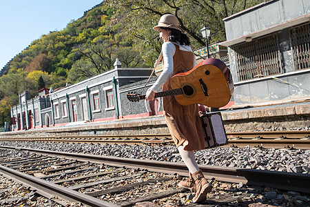 吉他美女自然无忧无虑道路青年女人在铁轨上行走背景