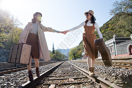 水平构图东方人火车站青年闺蜜手牵手走在铁轨上图片