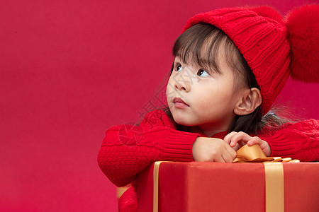 坐着户内幸福的小女孩趴在礼物包装盒上图片