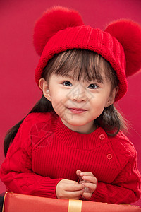春节新年微笑幸福的小女孩趴在礼物包装盒上图片
