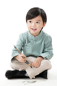 节日东方人春节小男孩盘腿坐着拿毛笔写字图片