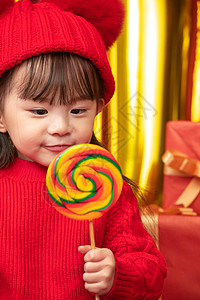祝福红色背景愉悦可爱的小女孩拿着棒棒糖图片