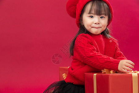 幸福传统节日红色可爱的小女孩趴在新年礼物上图片