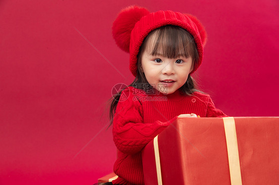 欢乐愉悦毛衣可爱的小女孩趴在新年礼物上图片