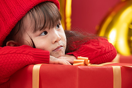 无忧无虑户内节日可爱的小女孩趴在新年礼物上图片