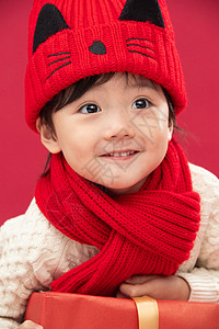 红色背景传统节日童年可爱的小男孩趴在新年礼物上图片