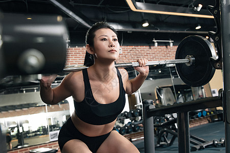 年轻女子在健身房练习抗杠铃图片