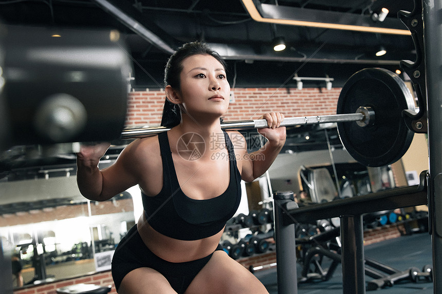 年轻女子在健身房练习抗杠铃图片