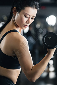 身材年轻女子在健身房练习举哑铃图片