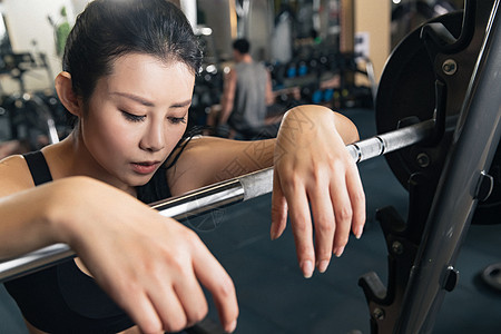 年轻女子趴在杠铃上休息图片