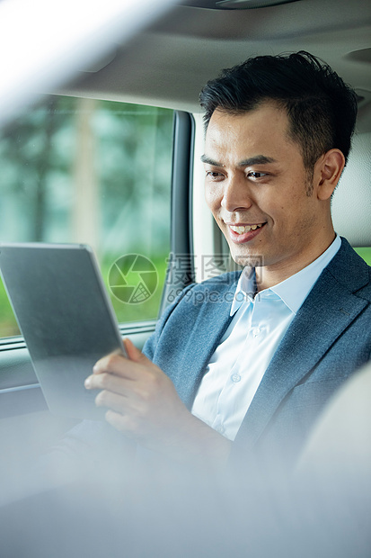 商务男士坐在汽车里使用平板电脑图片