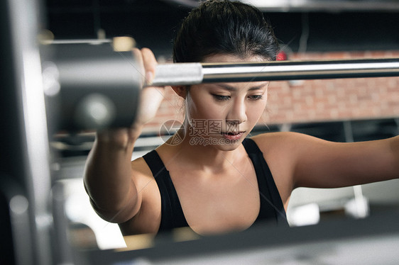 年轻女子在健身房练习抗杠铃图片