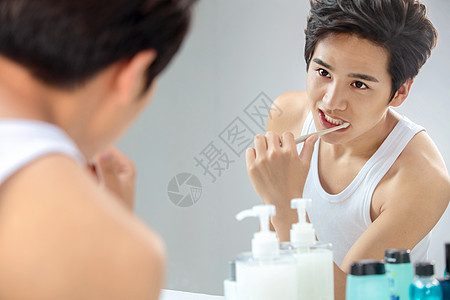 个人护理润肤露英俊年轻男人对着镜子在刷牙背景图片