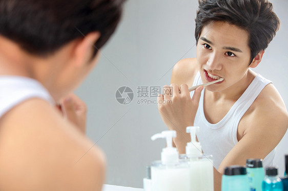 个人护理润肤露英俊年轻男人对着镜子在刷牙图片
