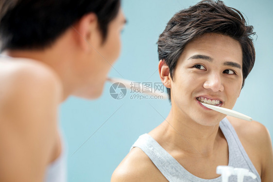 幸福人头和肩膀年轻男人对着镜子在刷牙图片