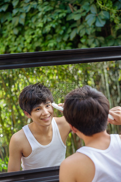 对着镜子洗脸的年轻男人图片