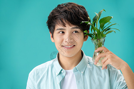 自然亚洲白掌拿着绿色植物的青年男人图片