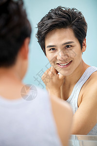 背心站着健康的自信的青年男人照镜子图片