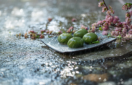 主食选择对焦新鲜雨中石板上的青团和桃花图片