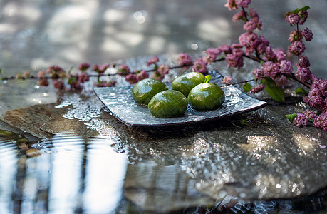 传统文化主食健康食物水面石板上的青团和桃花图片