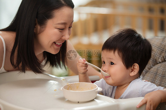 年轻妈妈喂餐椅上的宝宝吃饭图片