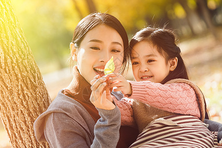 女人和叶子妈妈和女儿在户外玩耍背景