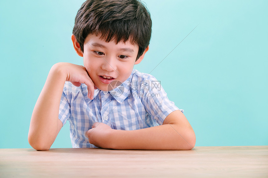 亚洲好奇心水平构图小男孩手托下巴趴在桌子上图片