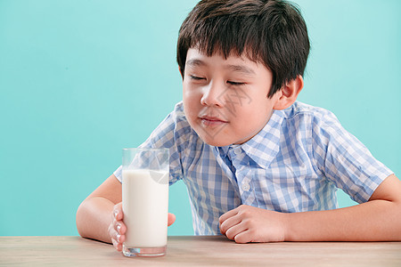 快乐可爱的清新小男孩看着一杯牛奶图片