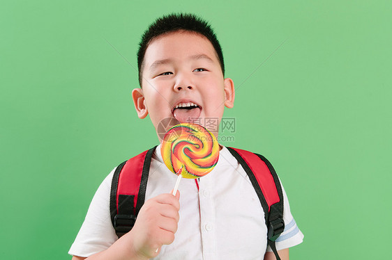水平构图快乐好奇心可爱的小男孩拿着棒棒糖图片