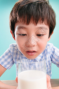 关爱可爱的8岁到9岁小男孩看着一杯牛奶图片