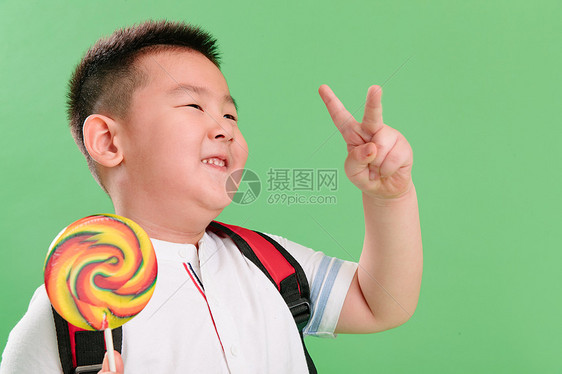 天真4岁到5岁做手势可爱的小男孩拿着棒棒糖图片