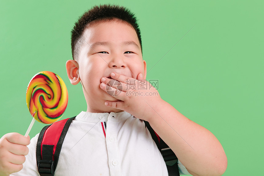 不看镜头学龄前儿童摄影可爱的小男孩拿着棒棒糖图片