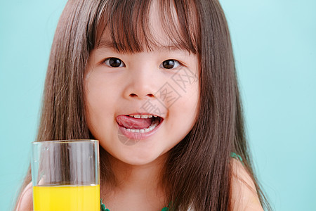小孩喝果汁注视镜头影棚拍摄微笑可爱的小女孩喝饮料背景