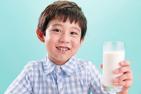蓝色背景亚洲休闲装小男孩和一杯牛奶图片