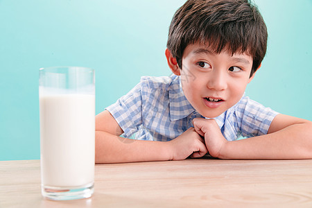可爱的户内好奇心小男孩和一杯牛奶图片
