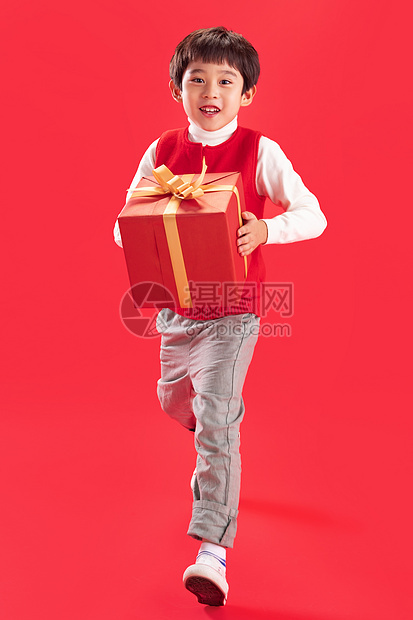 红色背景影棚拍摄摄影小男孩拿新年礼物图片