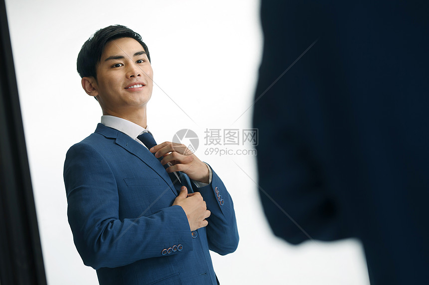 商务青年男人在镜子前穿衣服图片