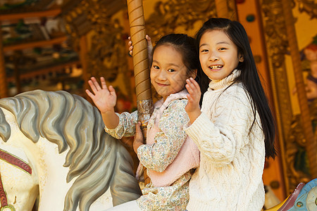 坐着健康生活方式北京两个小女孩在玩旋转木马图片