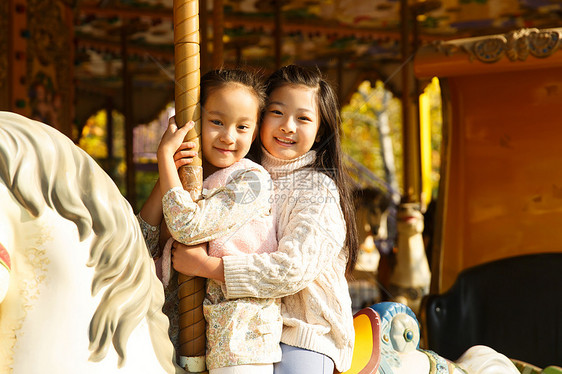 游乐园设施游乐场玩耍两个小女孩在玩旋转木马图片